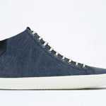 Side profile of mid top sneaker in denim blue canvas and leather upper, internal zip and white sole.