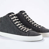 Vue de trois quarts avant de sneaker en toile noire et tige en cuir, fermeture à glissière interne et semelle blanche.