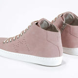 Three quarter back view of mid top sneaker in pink suede and leather upper, internal zip and white sole.