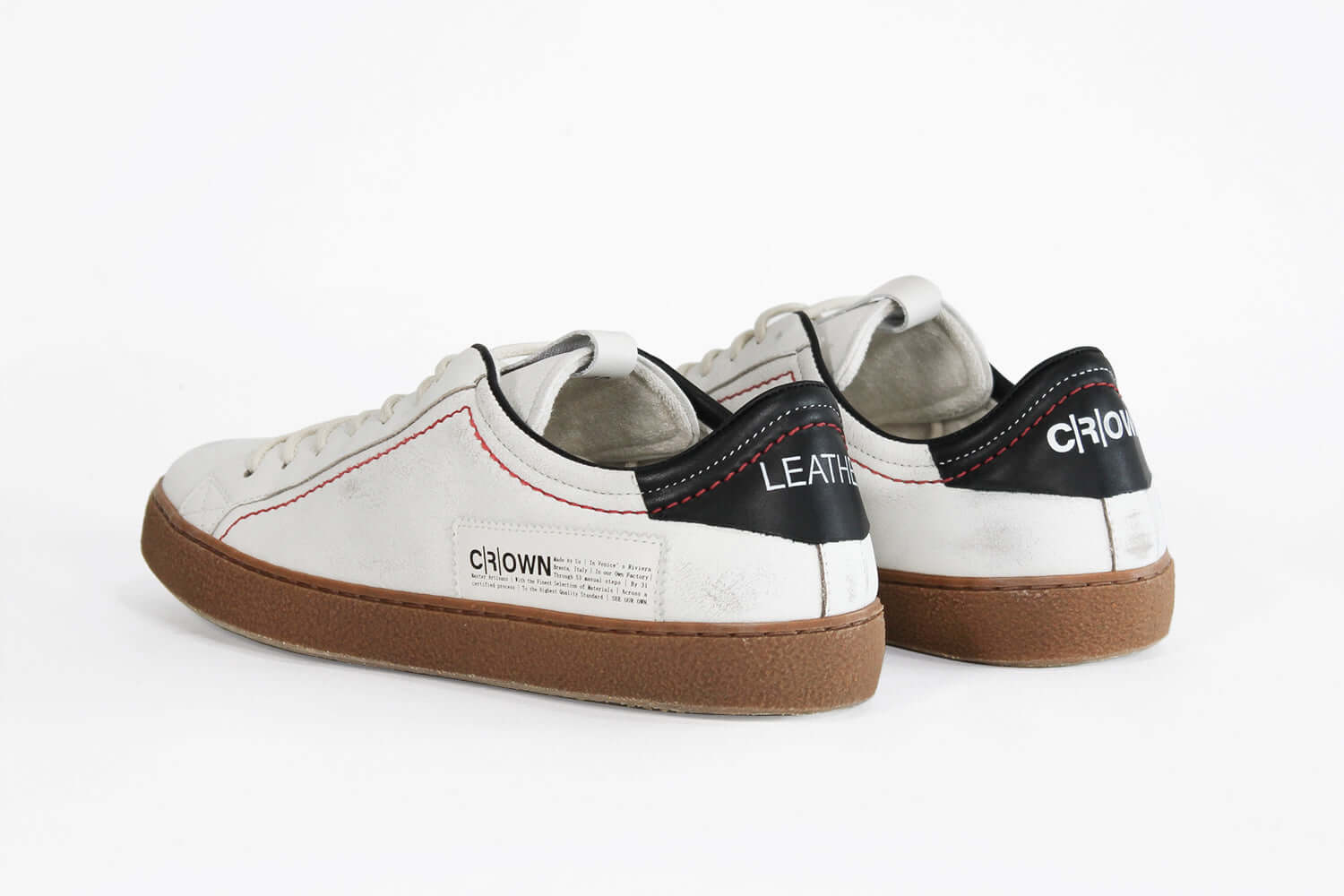 Vista posteriore della sneaker  BASSE bianca con accenti neri. Tomaia in pelle bianca invecchiata con cuciture rosse e suola in gomma scura.