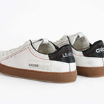 Vista posteriore della sneaker  BASSE bianca con accenti neri. Tomaia in pelle bianca invecchiata con cuciture rosse e suola in gomma scura.