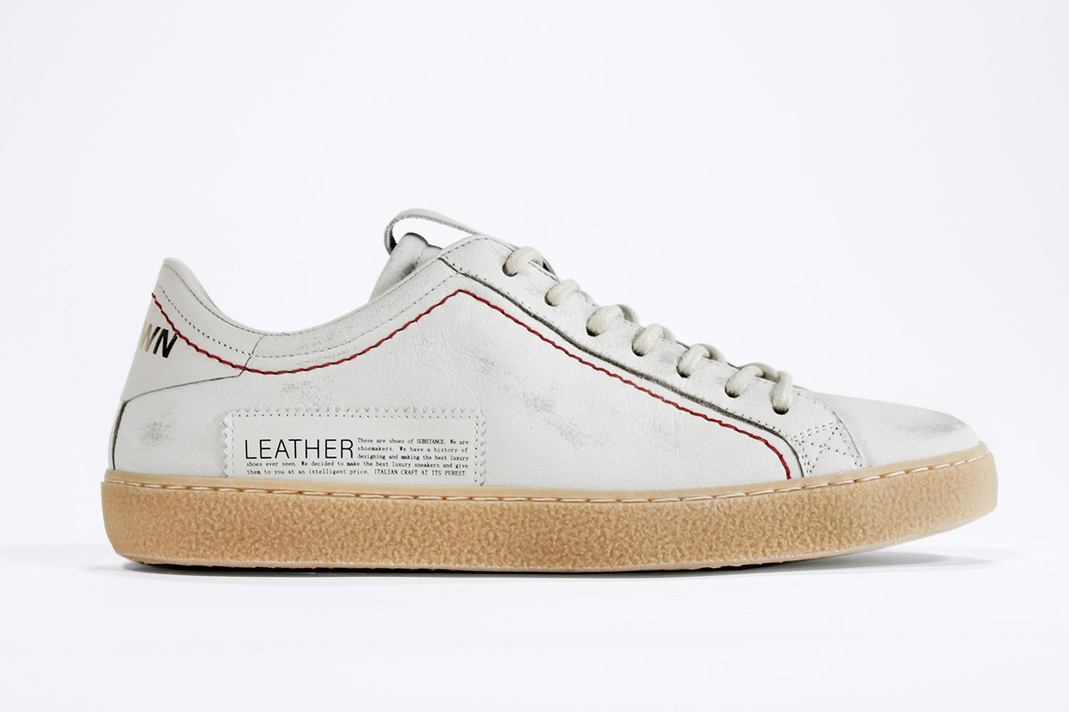 Profilo laterale della sneaker BASSE bianca. Tomaia in pelle bianca invecchiata con cuciture rosse e suola in gomma naturale.