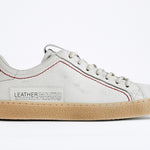 Profilo laterale della sneaker BASSE bianca. Tomaia in pelle bianca invecchiata con cuciture rosse e suola in gomma naturale.