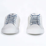 Front view of low top white sneaker with blue detailing and perforated crown logo on upper. Full leather upper and white rubber sole.