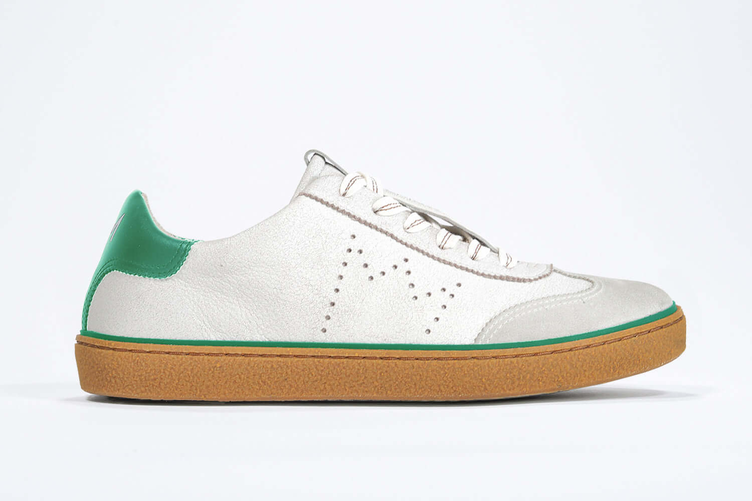Side view of low top retro sneaker in distressed white leather with green detailing and honey coloured recycled rubber sole.