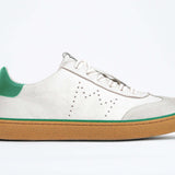 Side view of low top retro sneaker in distressed white leather with green detailing and honey coloured recycled rubber sole.