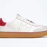 Side view of low top retro sneaker in distressed white leather with red detailing and honey coloured recycled rubber sole.
