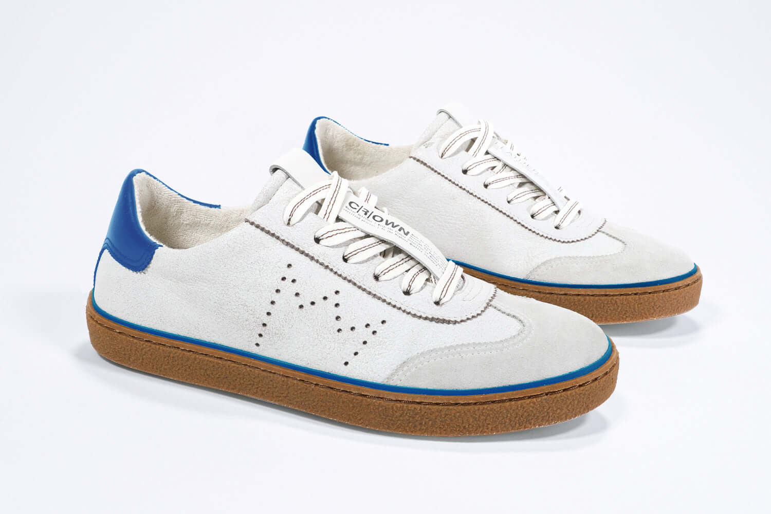 Three quarter front view of low top retro sneaker in distressed white leather with blue detailing and honey coloured recycled rubber sole.