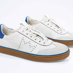 Three quarter front view of low top retro sneaker in distressed white leather with blue detailing and honey coloured recycled rubber sole.