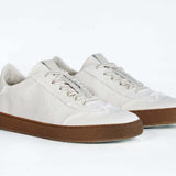 Dreiviertelansicht der Vorderseite eines sneaker aus weißem Canvas mit honigfarbener Sohle aus recyceltem Gummi.