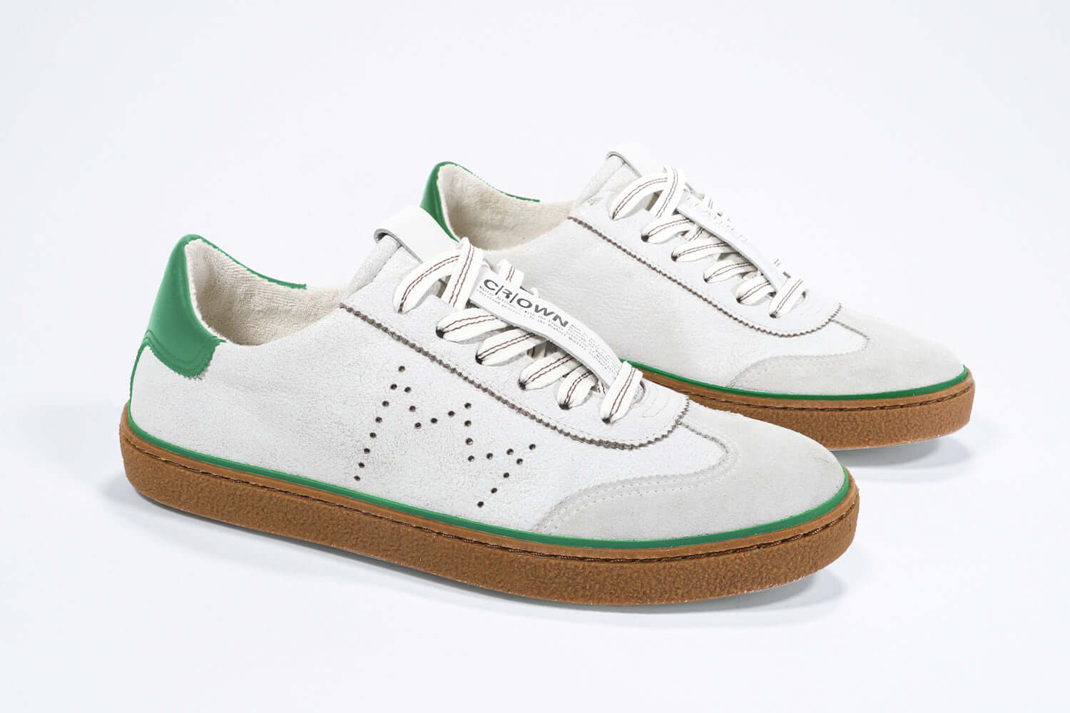 Three quarter front view of low top retro sneaker in distressed white leather with green detailing and honey coloured recycled rubber sole.