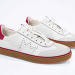 Three quarter front view of low top retro sneaker in distressed white leather with red detailing and honey coloured recycled rubber sole.
