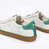 Back view of low top retro sneaker in distressed white leather with green detailing and honey coloured recycled rubber sole.