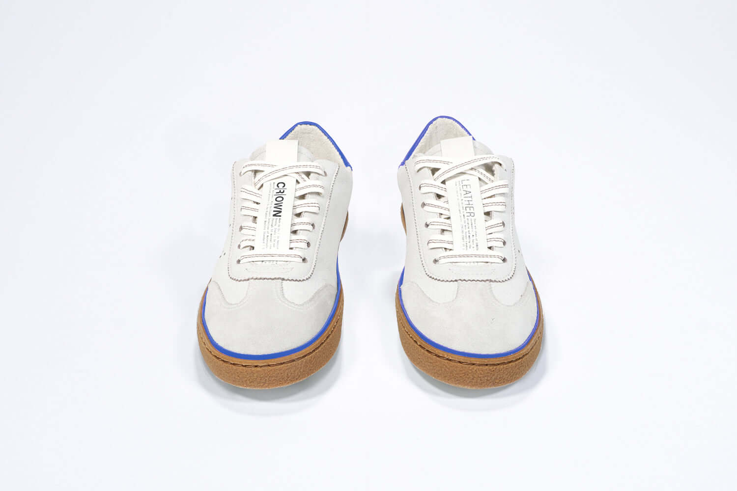 Front view of low top retro sneaker in distressed white leather with blue detailing and honey coloured recycled rubber sole.