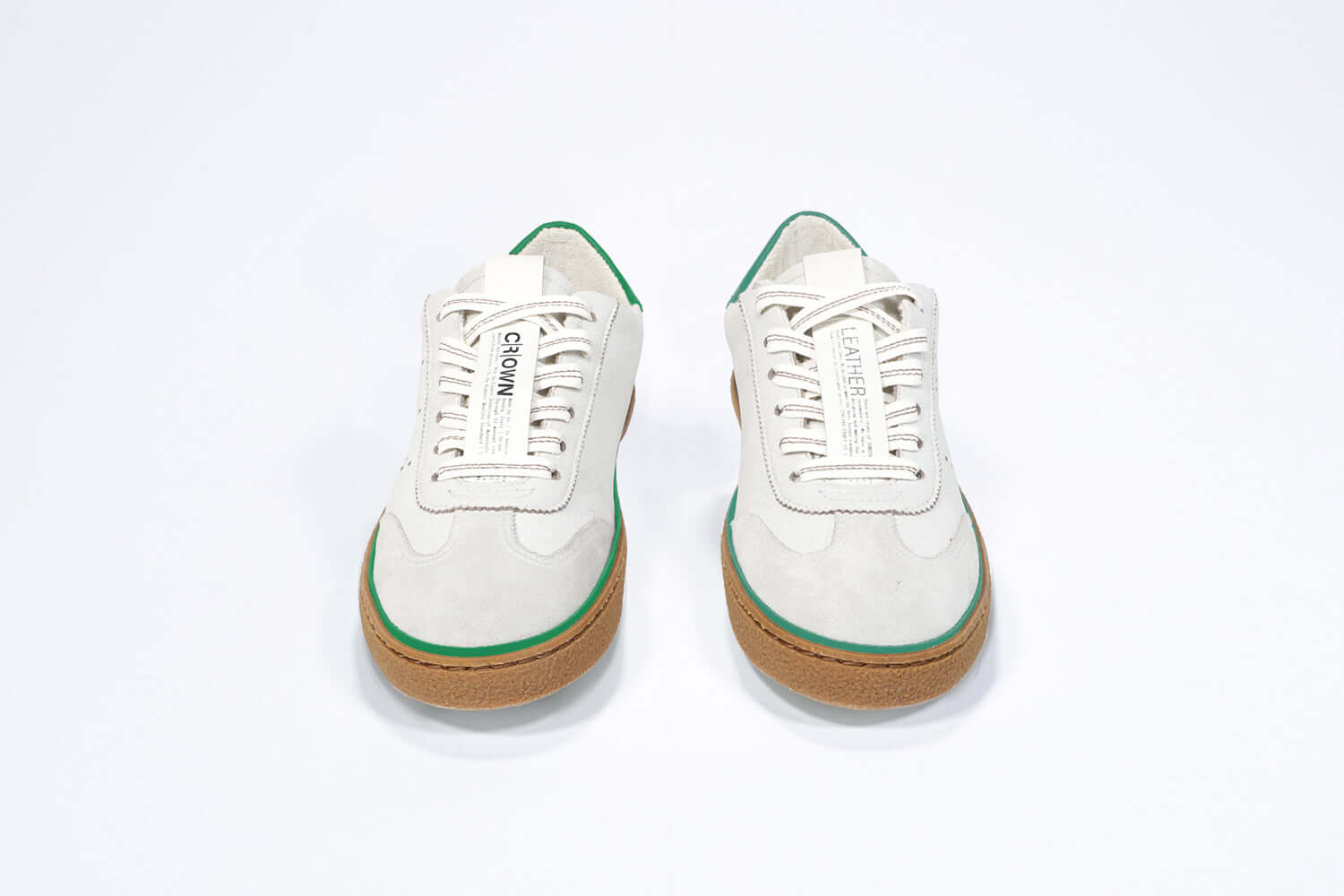 Front view of low top retro sneaker in distressed white leather with green detailing and honey coloured recycled rubber sole.