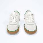 Front view of low top retro sneaker in distressed white leather with green detailing and honey coloured recycled rubber sole.