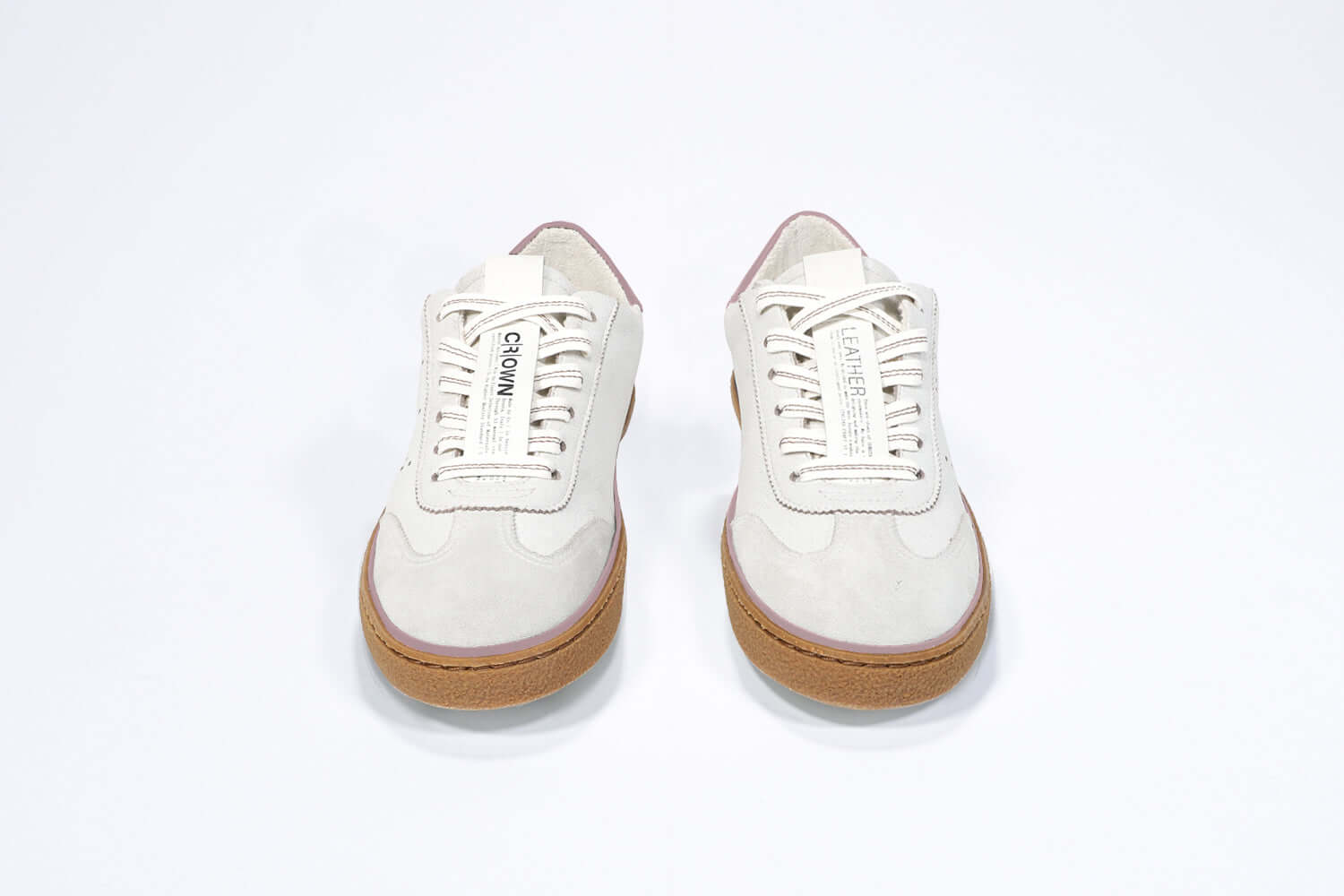 Front view of low top retro sneaker in distressed white leather with peach detailing and honey coloured recycled rubber sole.