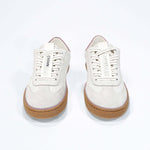 Front view of low top retro sneaker in distressed white leather with peach detailing and honey coloured recycled rubber sole.