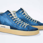 Three quarter front view of high top canvas sneaker. Canvas upper hand painted in gradated blue paint. Pale natural rubber sole.