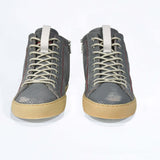 Front view of high top perforated aged grey leather sneaker with signature red stitching and a dark natural rubber sole.