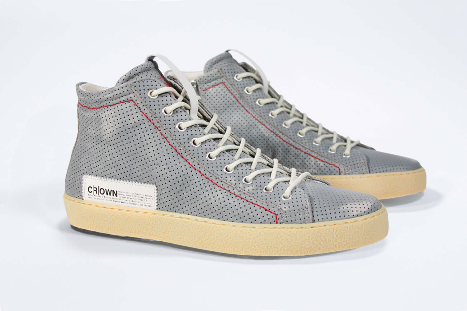 Three quarter front view of high top perforated aged grey leather sneaker with signature red stitching and a dark natural rubber sole.