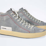 Three quarter front view of high top perforated aged grey leather sneaker with signature red stitching and a dark natural rubber sole.