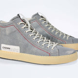 Three quarter front view of high top perforated aged grey leather sneaker with signature red stitching and a dark natural rubber sole.