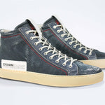 Three quarter front view of high top perforated aged navy leather sneaker with signature red stitching and a pale natural rubber sole.