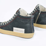 Back view of high top perforated aged navy leather sneaker with signature red stitching and a pale natural rubber sole.