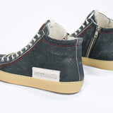 Back view of high top perforated aged navy leather sneaker with signature red stitching and a pale natural rubber sole.