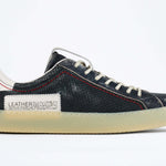 Side profile of low top aged navy sneaker with white accents. Perforated navy leather upper with red stitching and pale rubber sole.