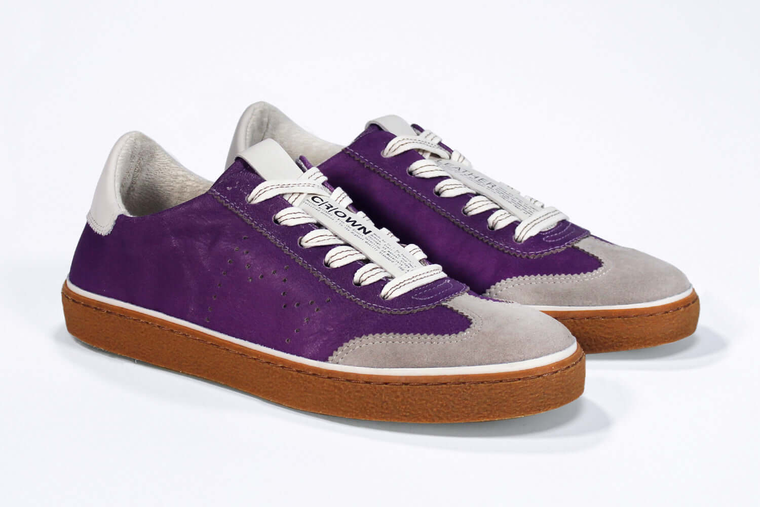 Three quarter front view of low top retro sneaker in distressed violet leather with white and grey detailing and honey coloured recycled rubber sole.