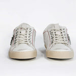 Front view of low top white studded sneaker. Aged white leather upper with silver studs and natural rubber sole.