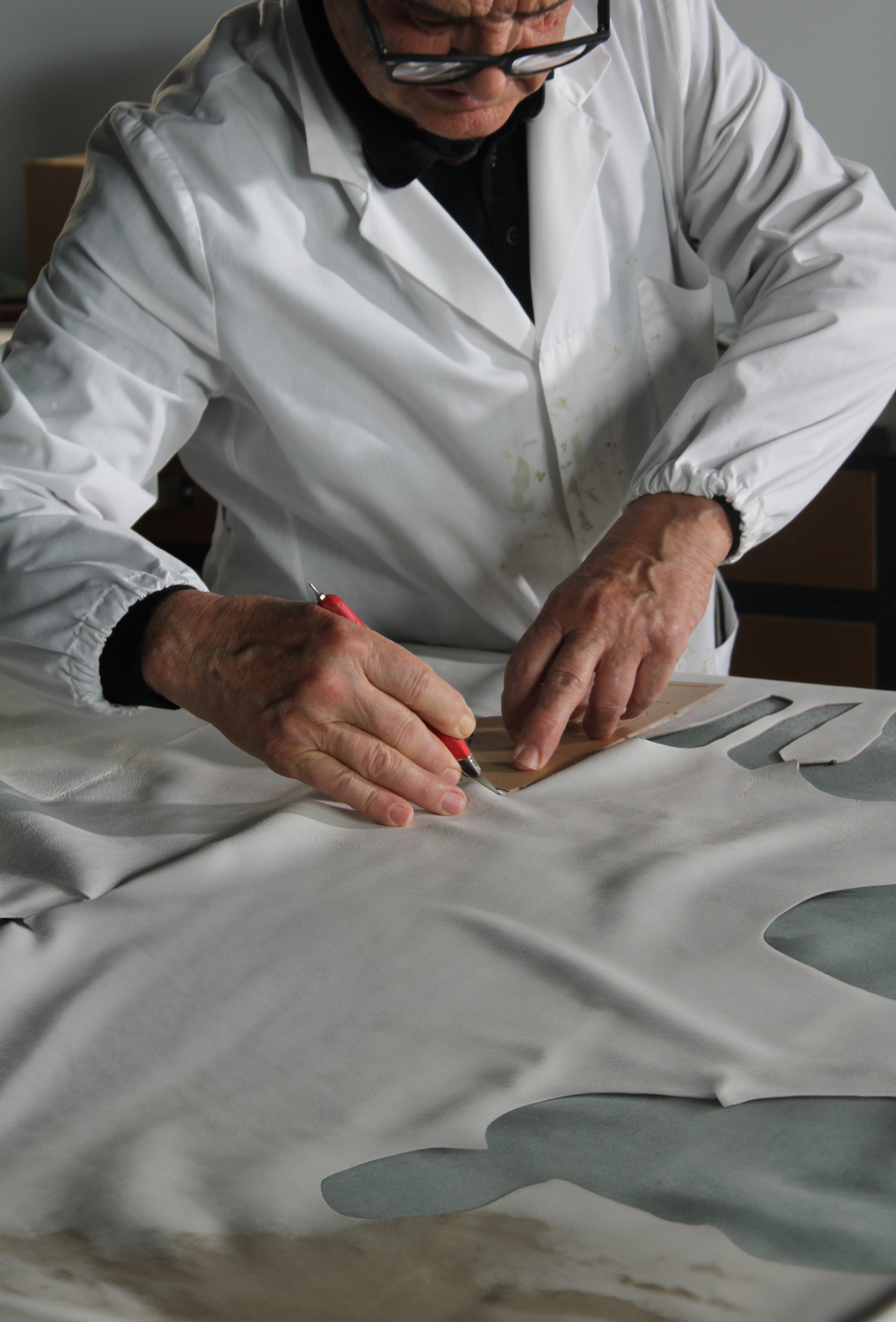 L'artigiano taglia pezzi di pelle per un Leather C|R|OWN sneaker .