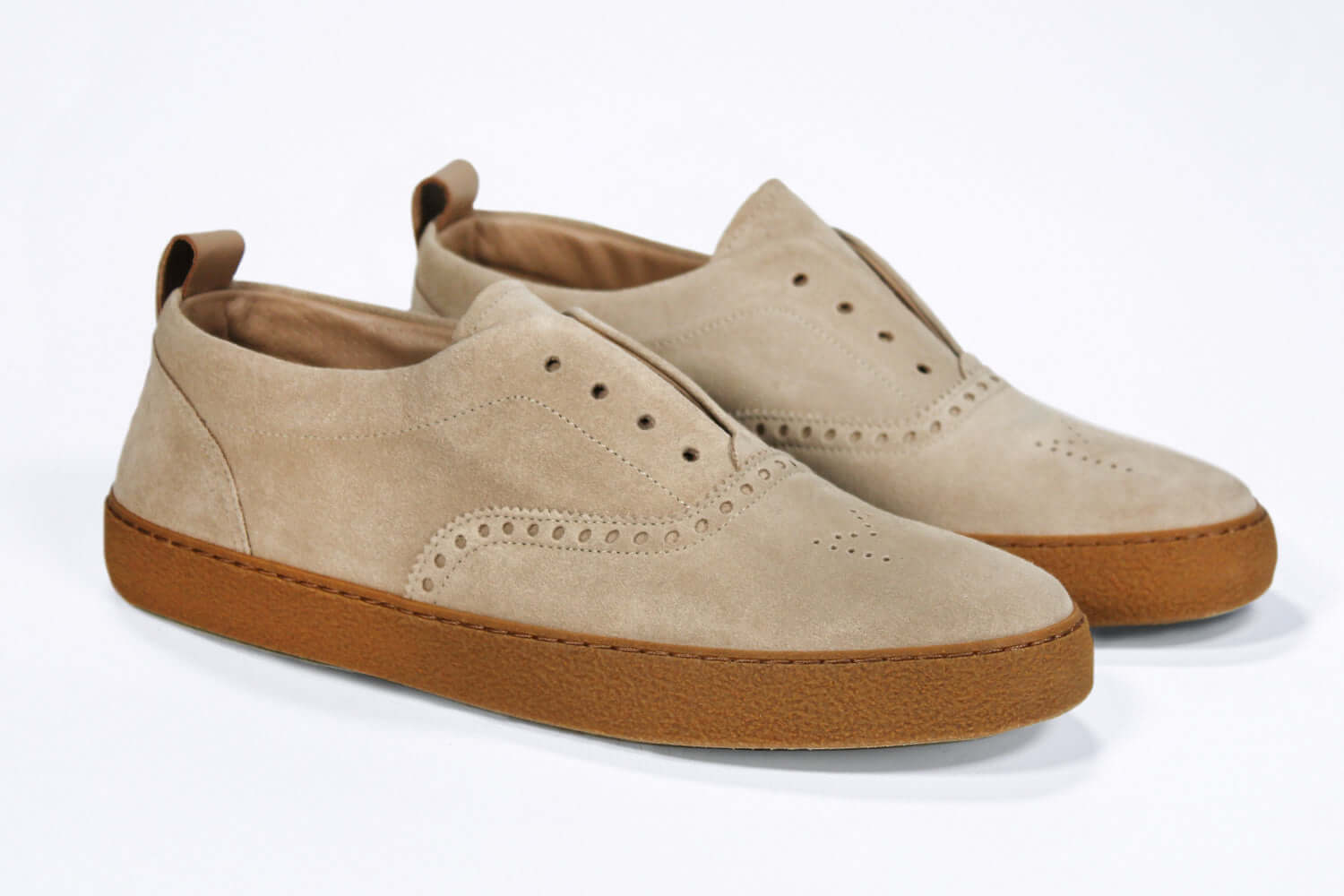 Three quarter front view of loafer style sneaker. Camel suede upper with perforated crown logo, elasticated tongue and a honey coloured recycled rubber sole.