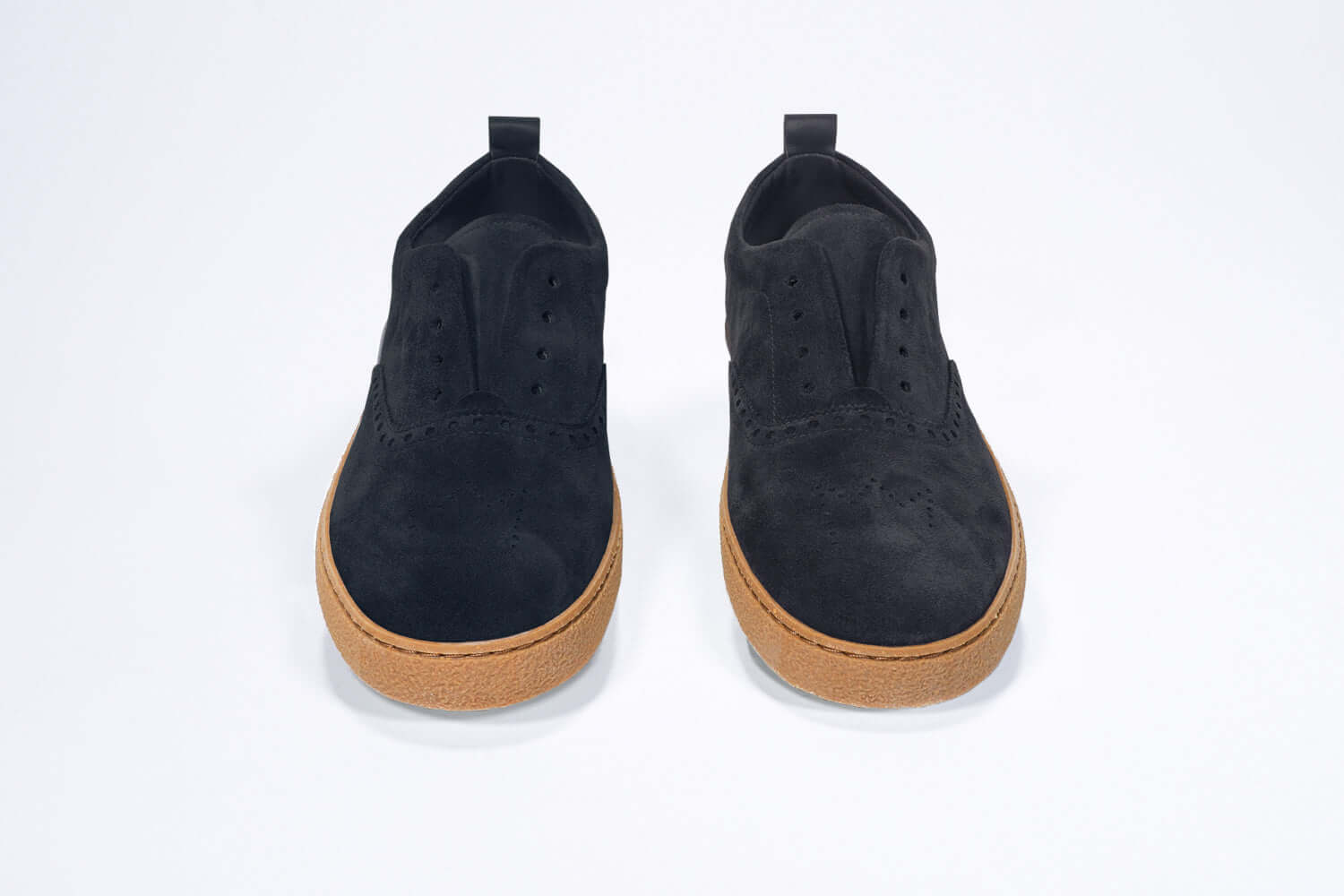 Front view of loafer style sneaker. Navy suede upper with perforated crown logo, elasticated tongue and a honey coloured recycled rubber sole.