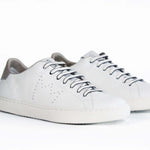 The quarter front view of low top white sneaker with beige detailing and perforated crown logo on upper. Full leather upper and white rubber sole.