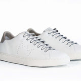The quarter front view of low top white sneaker with beige detailing and perforated crown logo on upper. Full leather upper and white rubber sole.