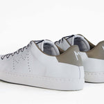 Back view of low top white sneaker with beige detailing and perforated crown logo on upper. Full leather upper and white rubber sole.