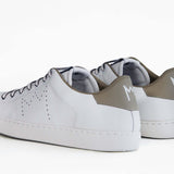 Back view of low top white sneaker with beige detailing and perforated crown logo on upper. Full leather upper and white rubber sole.
