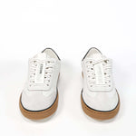 Front view of low top retro sneaker in distressed white leather with black detailing and honey coloured recycled rubber sole.