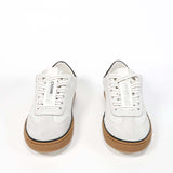 Front view of low top retro sneaker in distressed white leather with black detailing and honey coloured recycled rubber sole.