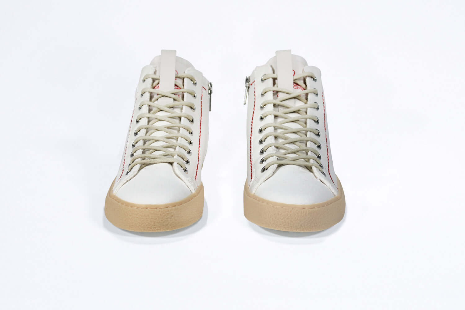 Front view of high top canvas sneaker. White canvas upper with signature red stitching and pale natural rubber sole.