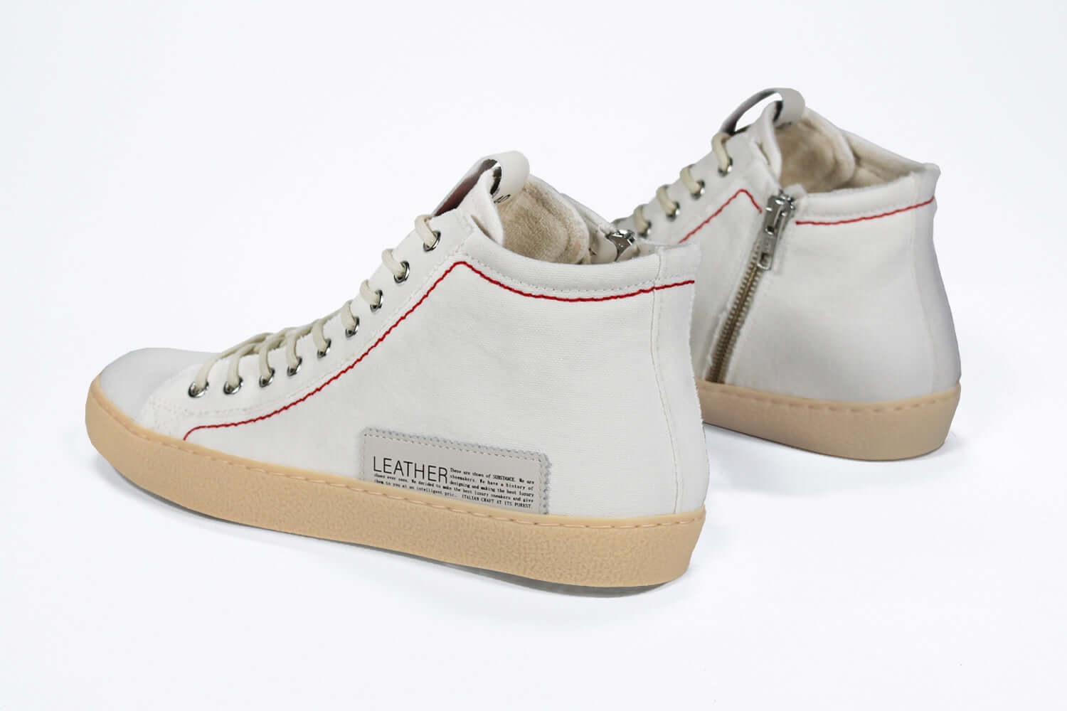 Back view of high top canvas sneaker. White canvas upper with signature red stitching and pale natural rubber sole.