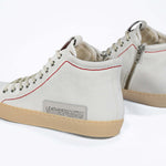 Back view of high top canvas sneaker. White canvas upper with signature red stitching and pale natural rubber sole.