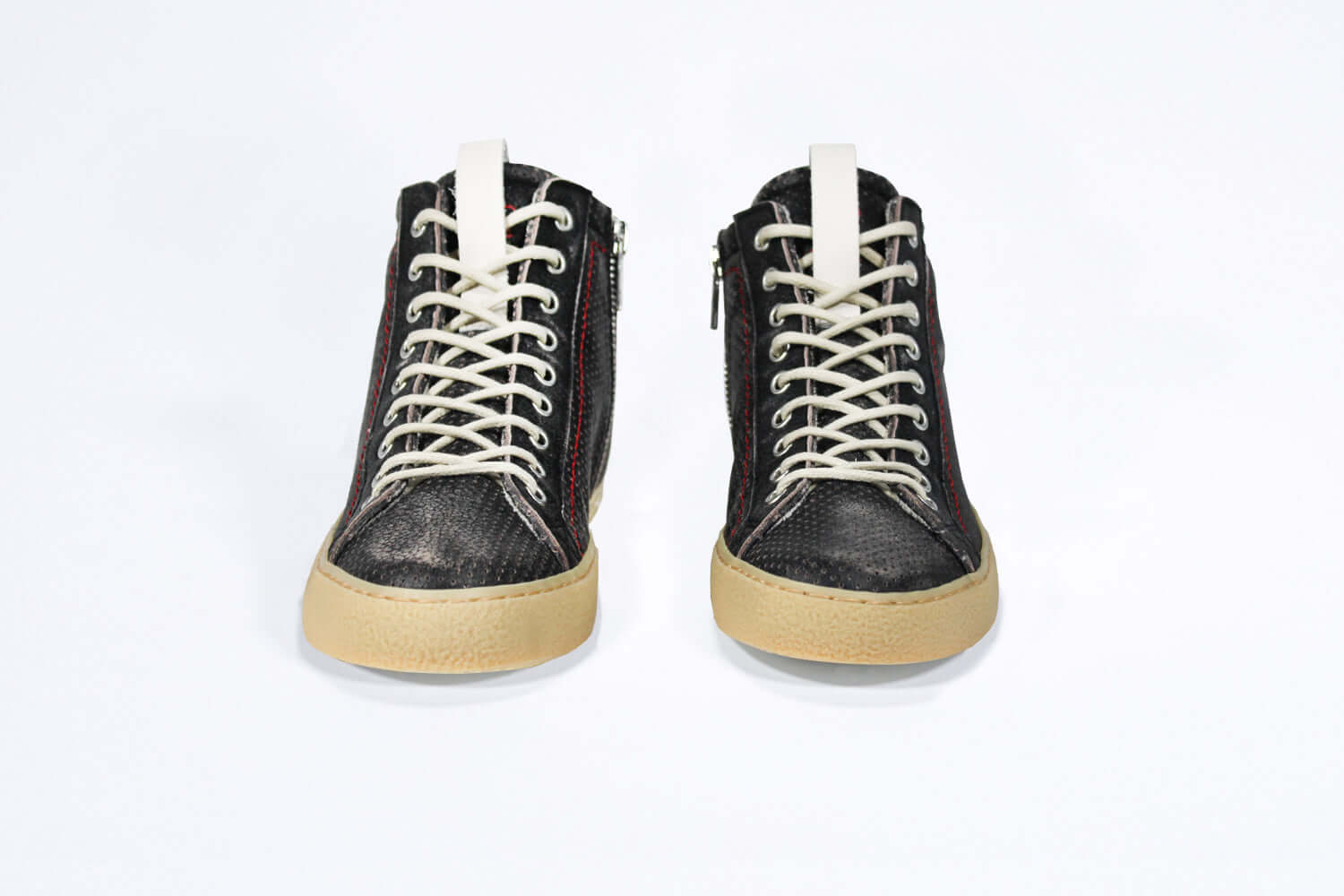 Front view of high top sneaker. Perforated distressed black leather sneakers with signature red stitching and pale natural rubber sole.