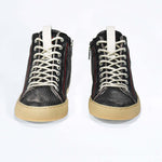 Front view of high top sneaker. Perforated distressed black leather sneakers with signature red stitching and pale natural rubber sole.