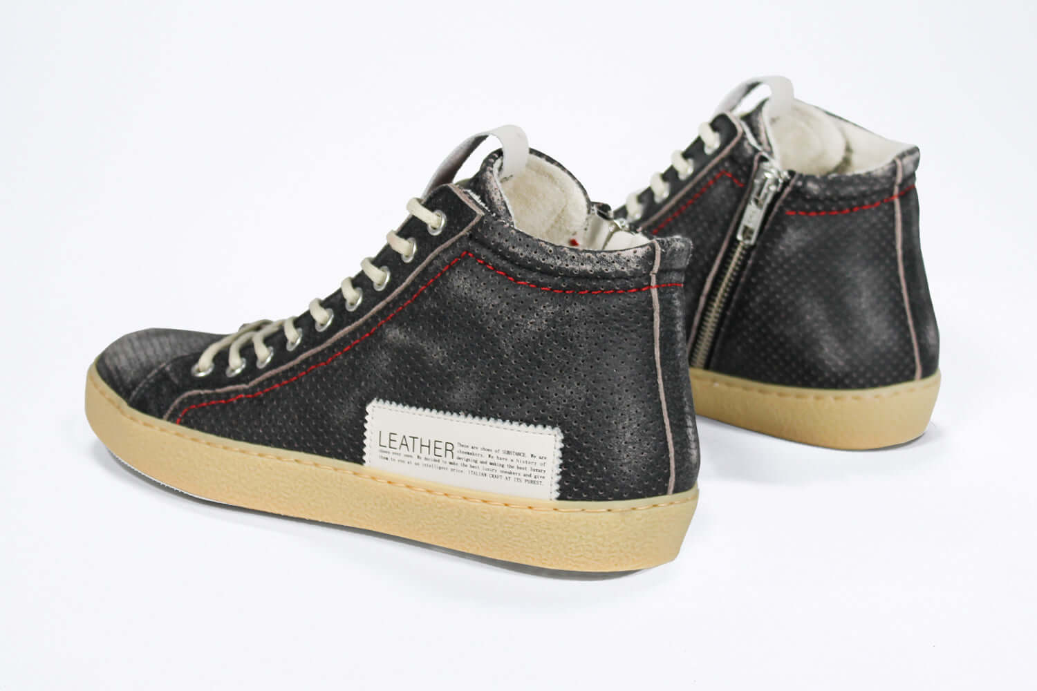 Back view of high top sneaker. Perforated distressed black leather sneakers with signature red stitching and pale natural rubber sole.
