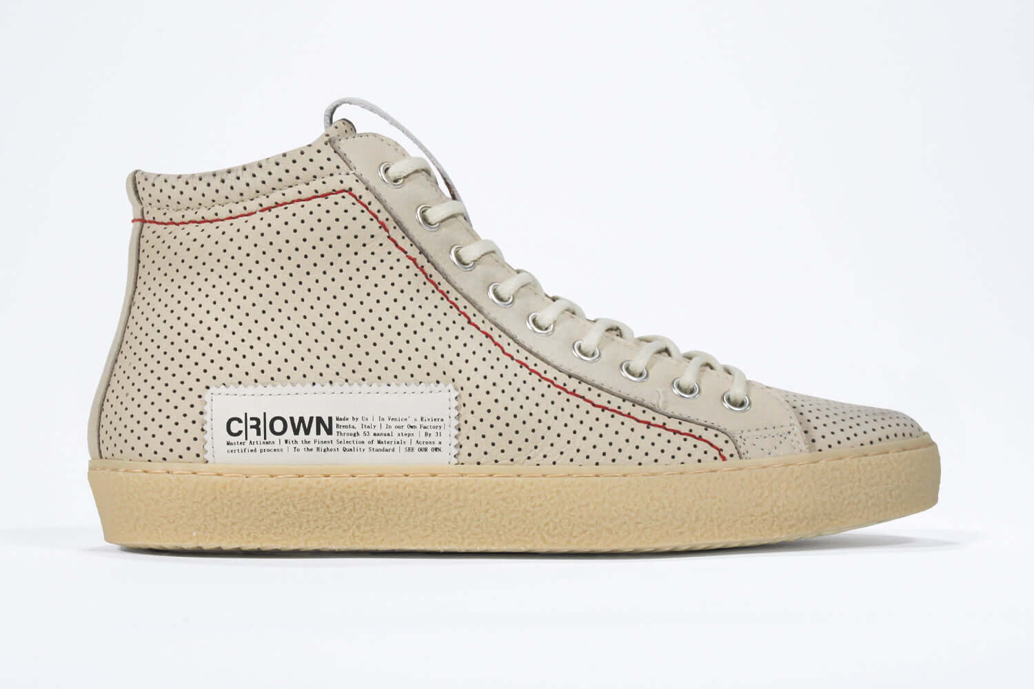 Side profile of high top sneaker. Perforated milk leather sneakers with signature red stitching and pale natural rubber sole.