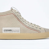 Side profile of high top sneaker. Perforated milk leather sneakers with signature red stitching and pale natural rubber sole.